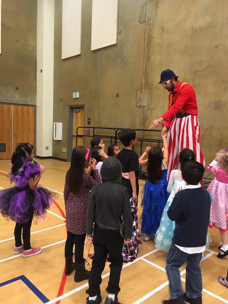 Nick greeting children on stilts at an indoor family event