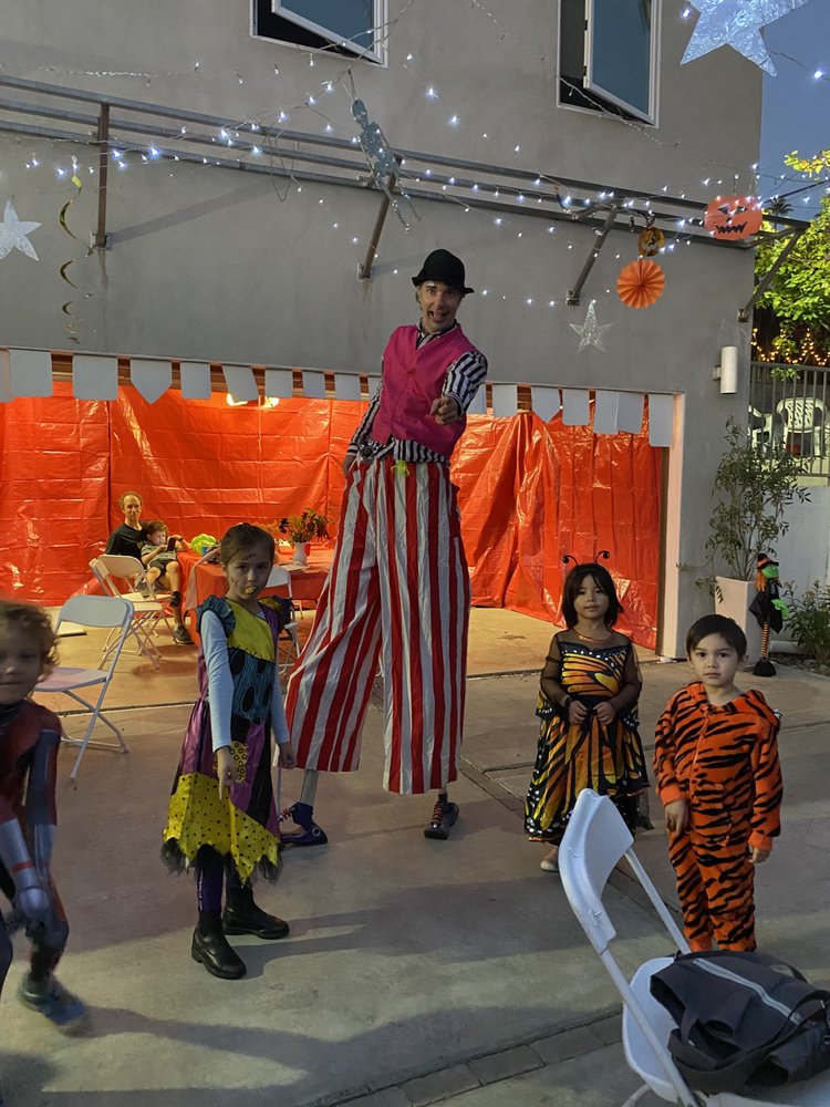 Nick stilt walking with children at a Halloween celebration